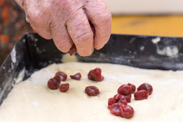 Obraz na płótnie Canvas Grandmothers hand preparing cherry pie