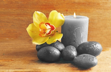 Spa stones with beautiful flowers and candles on wooden background