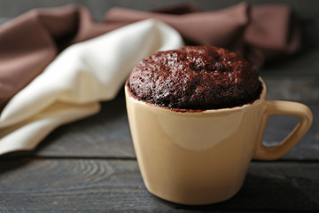 Chocolate fondant cake in cup on wooden table closeup