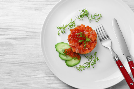 Delicious salmon tartare with red caviar on white plate