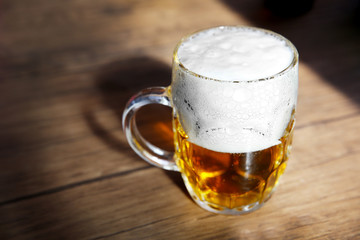 Glass mug of light beer on wooden table