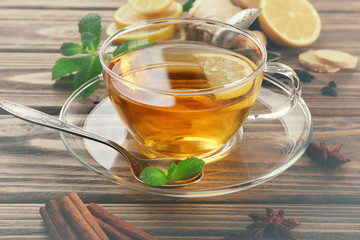 Cup of tea with ginger and cinnamon on wooden background