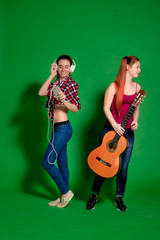 Two young women having fun, listening to music with headphones