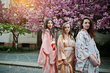 Three european girls wearing traditional japanese kimono backgro