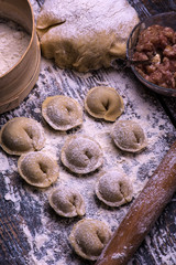 Fototapeta premium Raw meat dumplings. Ingredients for making dumplings: dough, minced meat, eggs on the wooden background