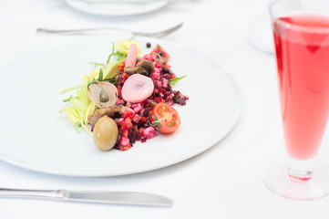 Russian Vinaigrette Salad Served on a Restaurant Table with a Glass of Fruit Juice