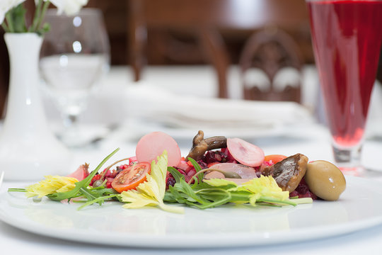 Russian Vinaigrette Salad Served on a Restaurant Table with a Glass of Fruit Juice