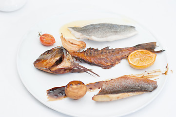 Menu for Pirate Party; smoked fish fillet with fish bones served with smoked lemon and onion on a white plate