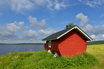Finnish sauna on the shore of the blue lake summer day. Northern Finland, Lapland