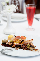 Sliced Polenta Cornmeal with Roasted and Fresh Vegetables Served on a white plate with fork and knife