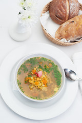 Lentil Soup Served in a white Bowl with spoon and freshly baked bread