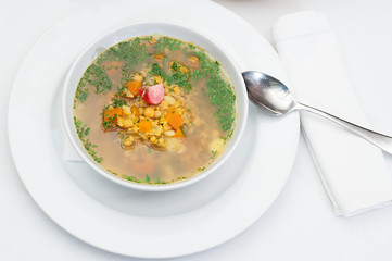 Lentil Soup Served in a White Bowl with Spoon on a restaurant table
