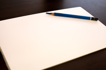 Drawing Pencil and white paper on dark brown background.