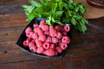 Red raspberries in bowl on wooden background