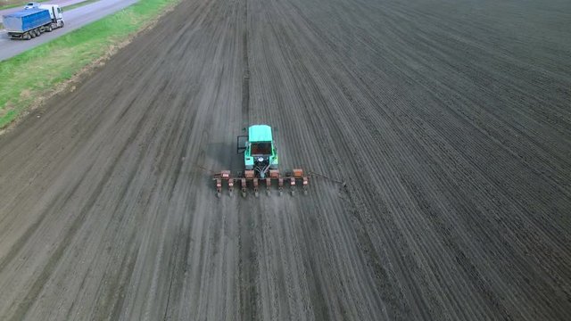 Tractor in a field brings fertilizer into the soil. Early spring. aerial survey 4k