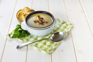 Mushroom soup with a bread roll and parsley