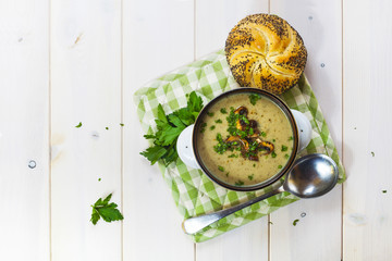 Mushroom soup with a bread roll and parsley