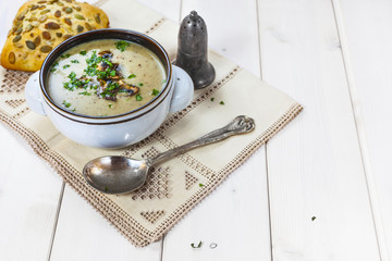 Mushroom soup with a bread roll and parsley