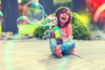 Little girl playing with soap bubbles machine