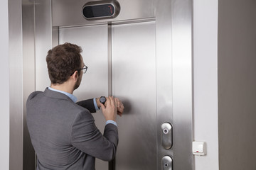 Businessman looking at his watch while waiting for the elevator 