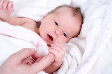 Kleines Baby greift nach Finger der Mutter