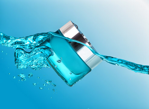 The blue jar of moisturizing cream in the blue water wave  with  air bubbles and water drops on the blue water background
