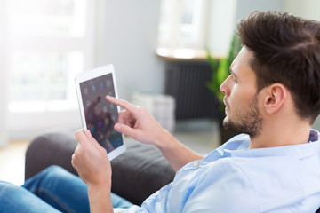 Obraz na płótnie Canvas Man sitting on couch with digital tablet