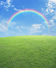 Regenboog met groen grasveld over blauwe lucht, natuurachtergrond