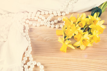 Beautiful white cloth, pearl beads and yellow daffodil on  the table.