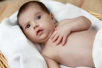 Fototapeta na wymiar Cute shocked newborn baby lying in wicker basket