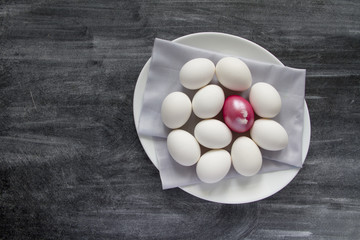 Easter Egg and white eggs on white plate. Top view with copy spa
