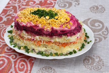Colorful salad with herring and vegetables on the plate