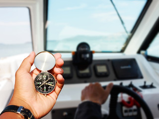 Man hand with a black and silver compass inThe yacht control panel. Gearbox switch detail,