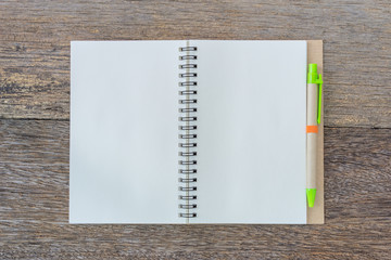 Open notebook on wooden background with pen.
