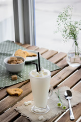 Glass with milkshake  and cookie in cafe.
