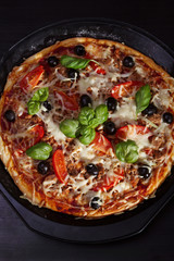 pizza with onions, tuna, tomatoes and olives on wooden table