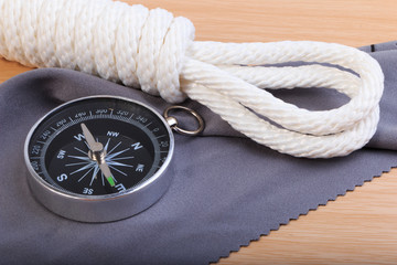 Fototapeta na wymiar Orderliness white scout rope, compass and fabric on wooden table.