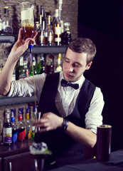 young man working as a bartender in a nightclub bar