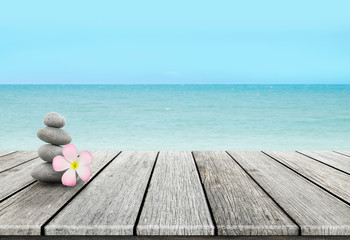Stack of pebble stones and Plumeria at the beach on a wooden surface