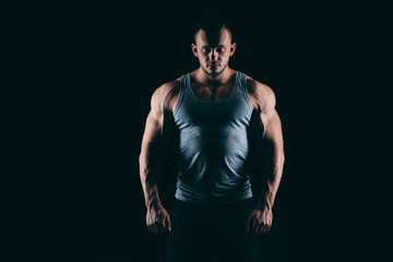 Naklejka premium Silhouette of a strong fighter. Confident young fitness man with hands and clenched fists. Dramatic light.