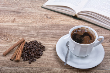 A cup of coffee with a book on a wooden background