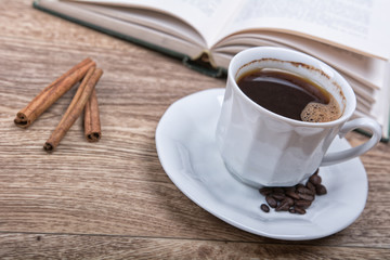 A cup of coffee with a book on a wooden background