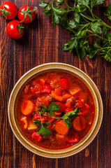 Goulash or stew in bowl served with parsley on wooden background