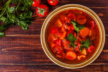 Goulash or stew in bowl served with parsley on wooden background