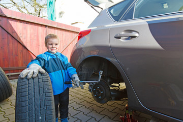 Boy mounted tires on a car.
