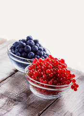 Berries mix in a studio in two glass jars on old rustic wooden table white background