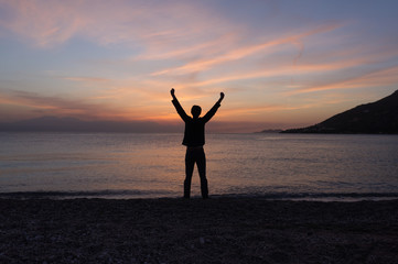 Fototapeta na wymiar Happy free man standing on the beach at sunset