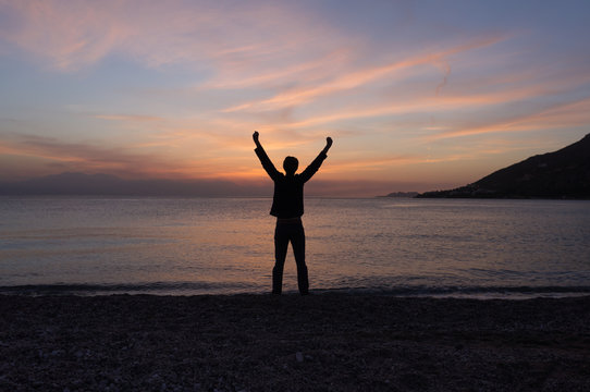 Happy free man standing on the beach at sunset