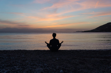 Silhouette of man meditating on the beach