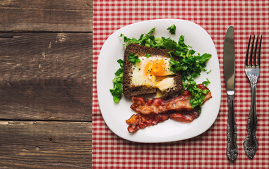 Fried egg in rye bread with bacon and parsley